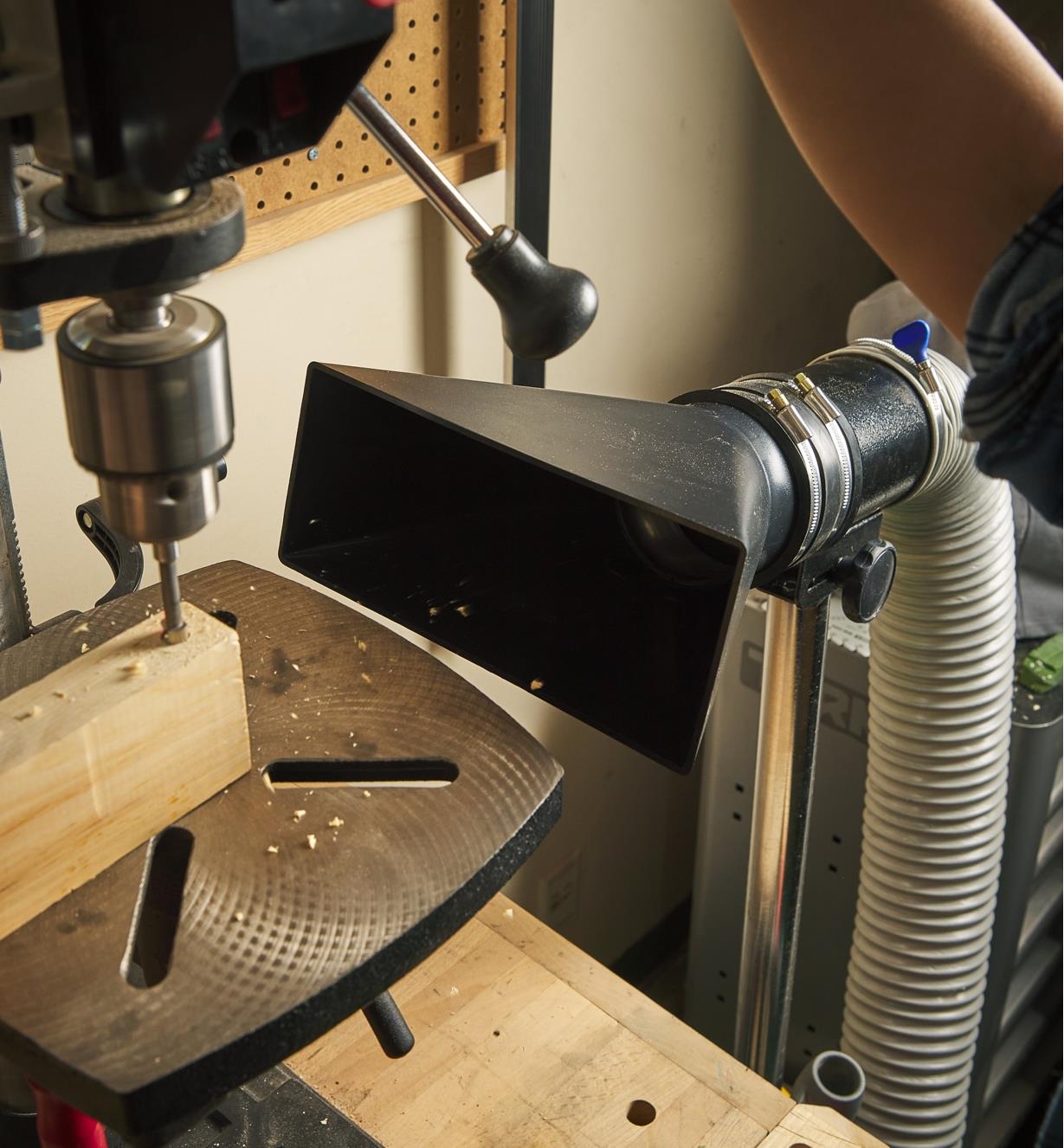 A medium dust hood on a stand next to a drill press